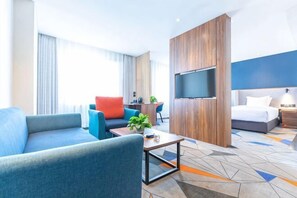 Ein Hotelzimmer mit einem Bett, einem Fernseher, einer Sitzecke mit Couchtisch und einem Schreibtisch mit Stuhl.