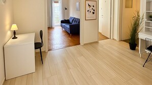 Un espacio habitable amplio con un sofá, una mesita con una lámpara y una planta en maceta.