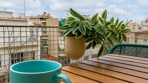 Una taza de café color turquesa sobre una mesa de madera, con una pequeña planta en maceta a un lado.