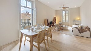 Un salon spacieux comprenant un coin repas, de grandes fenêtres et une cheminée.
