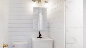 Een badkamer met witte betegelde muren, een witte wastafel en een toilet.