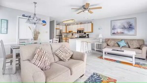 Een moderne woonkamer met een bank, salontafel en een eethoek met stoelen en een tafel.