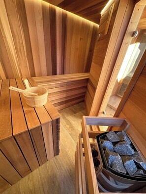 Een houten sauna met banken en een steenoven.