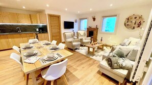 A modern living room with a dining area, wooden flooring, white furniture, a fireplace, and a TV mounted on the wall. - Le Janus - at the foot of the slopes, terrace with sauna, garage (Montgenèvre)