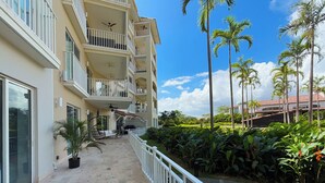 Un hotel de varios pisos con balcones, mobiliario exterior y un jard ín con palmeras.