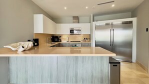Una cocina moderna con una isla central, electrodomésticos de acero inoxidable y armarios de tonos claros.