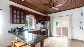 A kitchen with wooden cabinets, a granite countertop, and a built-in oven. - Tropical Sunset at Sunset Villas in West End, 2 bd Condo  (West End)