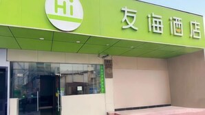 A building with a green sign that reads 'Hi' and '友海酒店' indicating a hotel. - Youhai Hotel (Shanghai University Qinghe Road) (Shanghai)