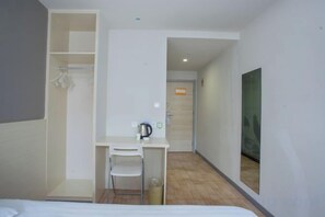 A hotel room with a bed, a desk with a chair, a small trash bin, a coat rack, and a door leading to another room. - Youhai Hotel (Shanghai University Qinghe Road) (Shanghai)