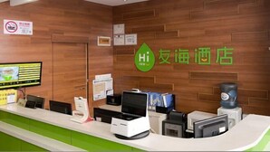A hotel reception desk with a wooden wall, a green counter, a digital screen, and a 'Hi Inn' sign. - Youhai Hotel (Shanghai University Qinghe Road) (Shanghai)