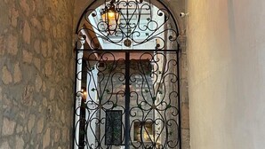 An arched doorway with intricate wrought iron detailing and a lantern above. - Casa Serdán Suites & Events (Morelia)