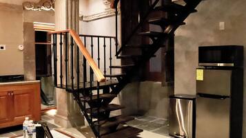 Una cucina con una scala in legno, un frigorifero in acciaio inossidabile e un forno a microonde.