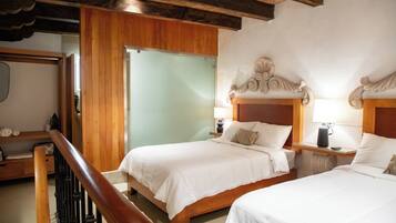 A hotel room with two beds, wooden headboards, a wooden staircase, and a wooden ceiling.