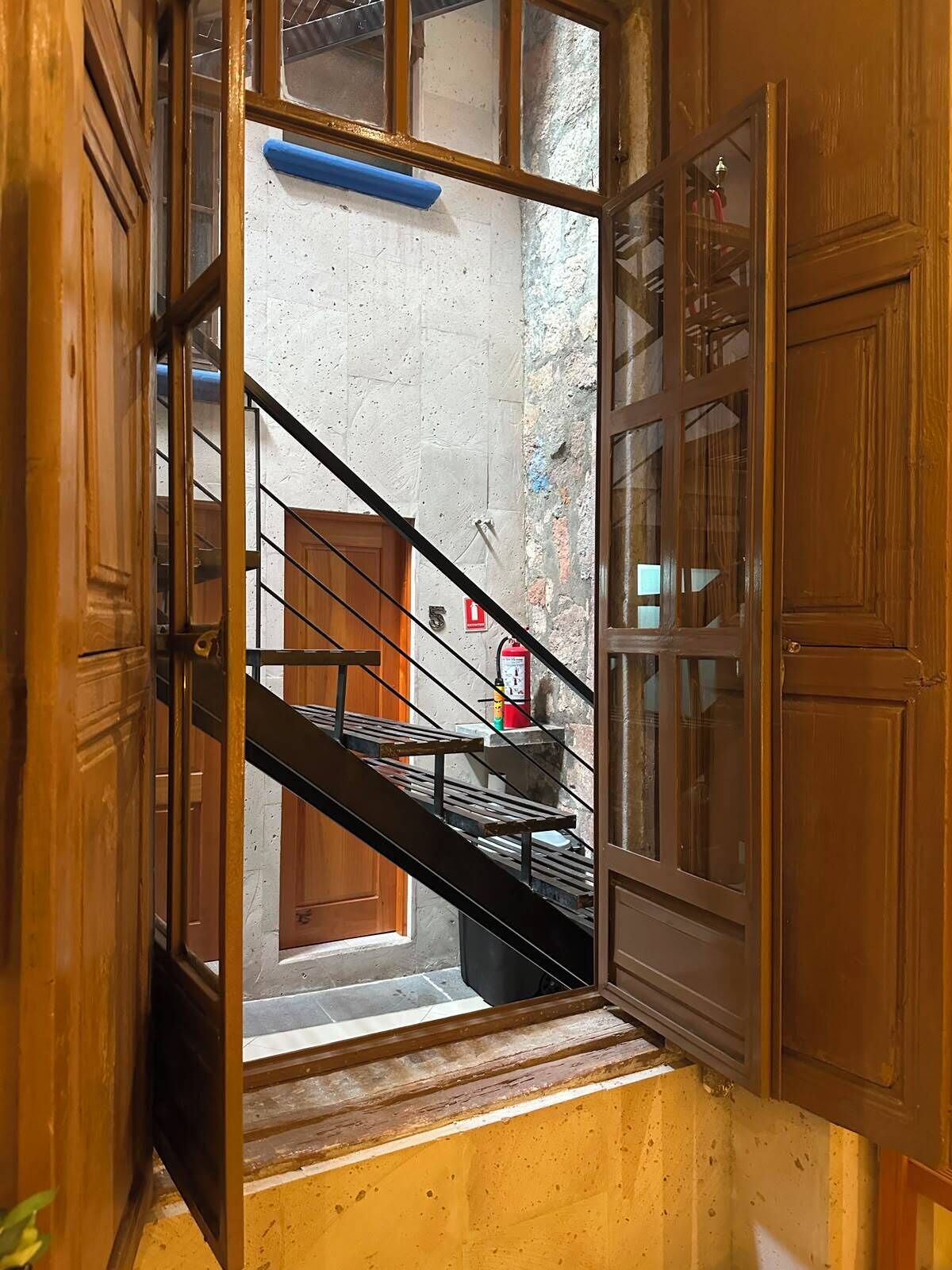 A wooden staircase with a metal handrail leading to a landing.