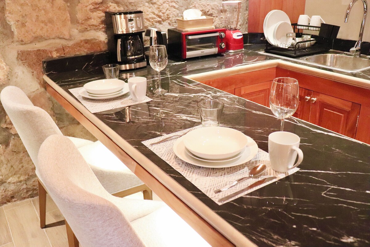 A modern kitchen with a marble countertop, a coffee maker, a toaster, and a sink.