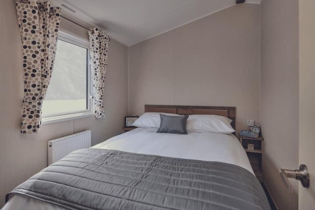 Une chambre à coucher avec un lit, des rideaux, une table de chevet et une fenêtre.