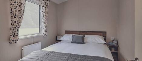 Une chambre à coucher avec un lit, des rideaux, une table de chevet et une fenêtre.