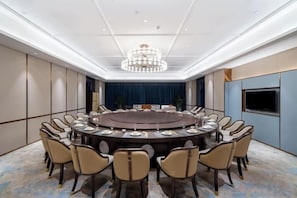A conference room with a round table, chairs, and a chandelier.