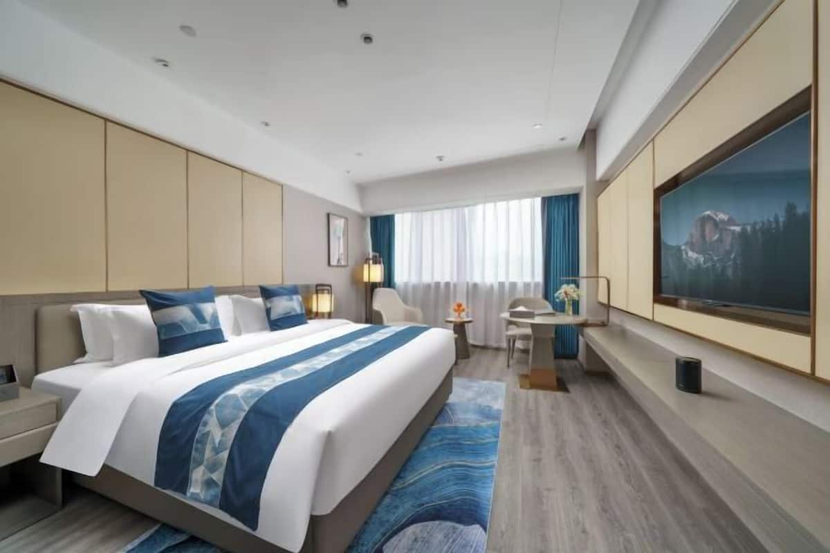 Une chambre d’hôtel moderne, dotée d’un grand lit, d’un bureau et d’une télévision.