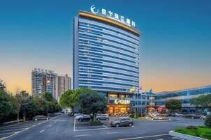 A modern hotel with a curved facade, multiple floors, and a parking lot in front.