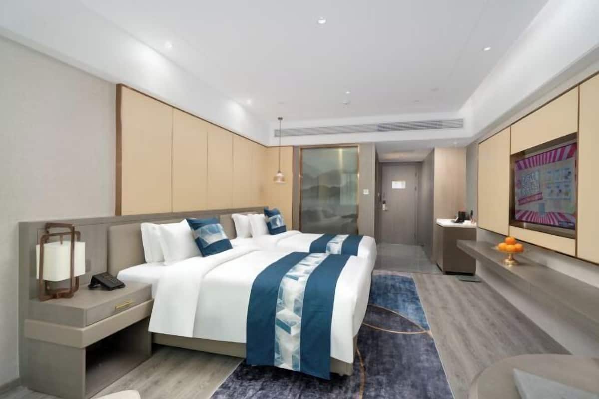 Une chambre d’hôtel moderne, dotée d’un grand lit, de tables de chevet, d’un bureau et d’une télévision.