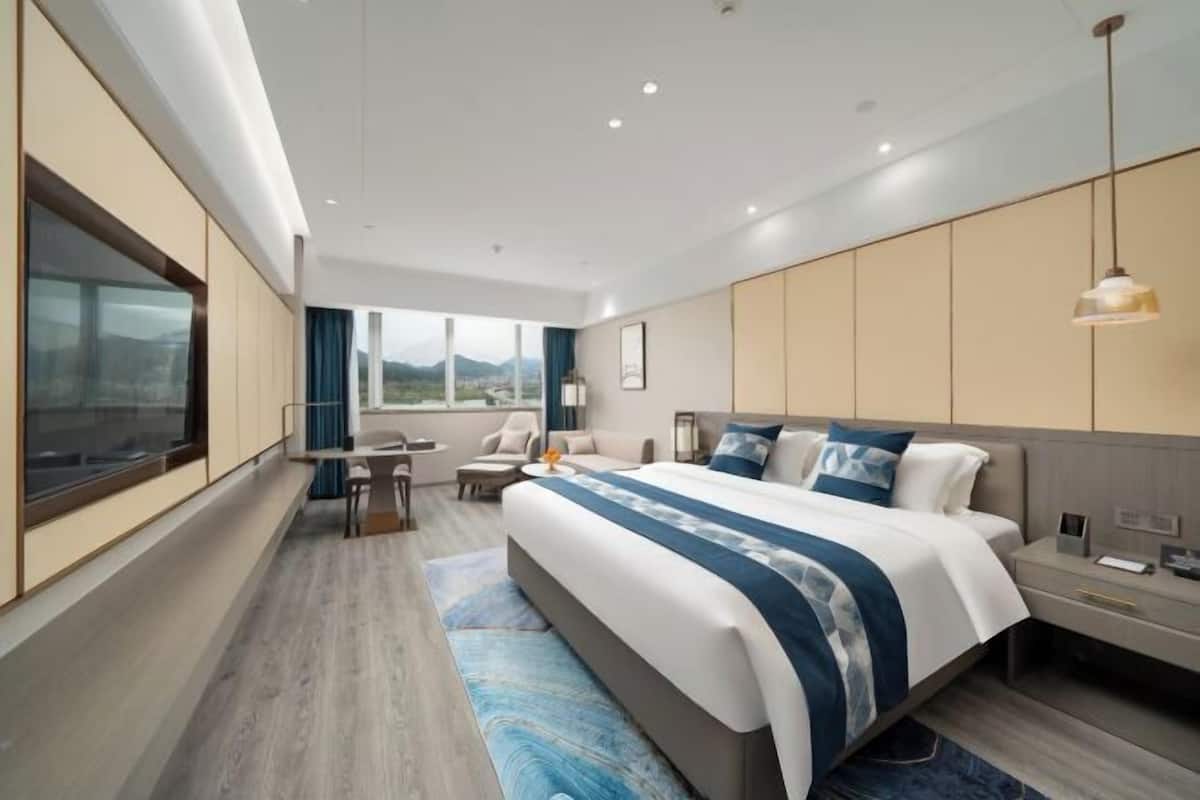 Une chambre d’hôtel moderne avec un grand lit, un bureau et une vue sur les montagnes.