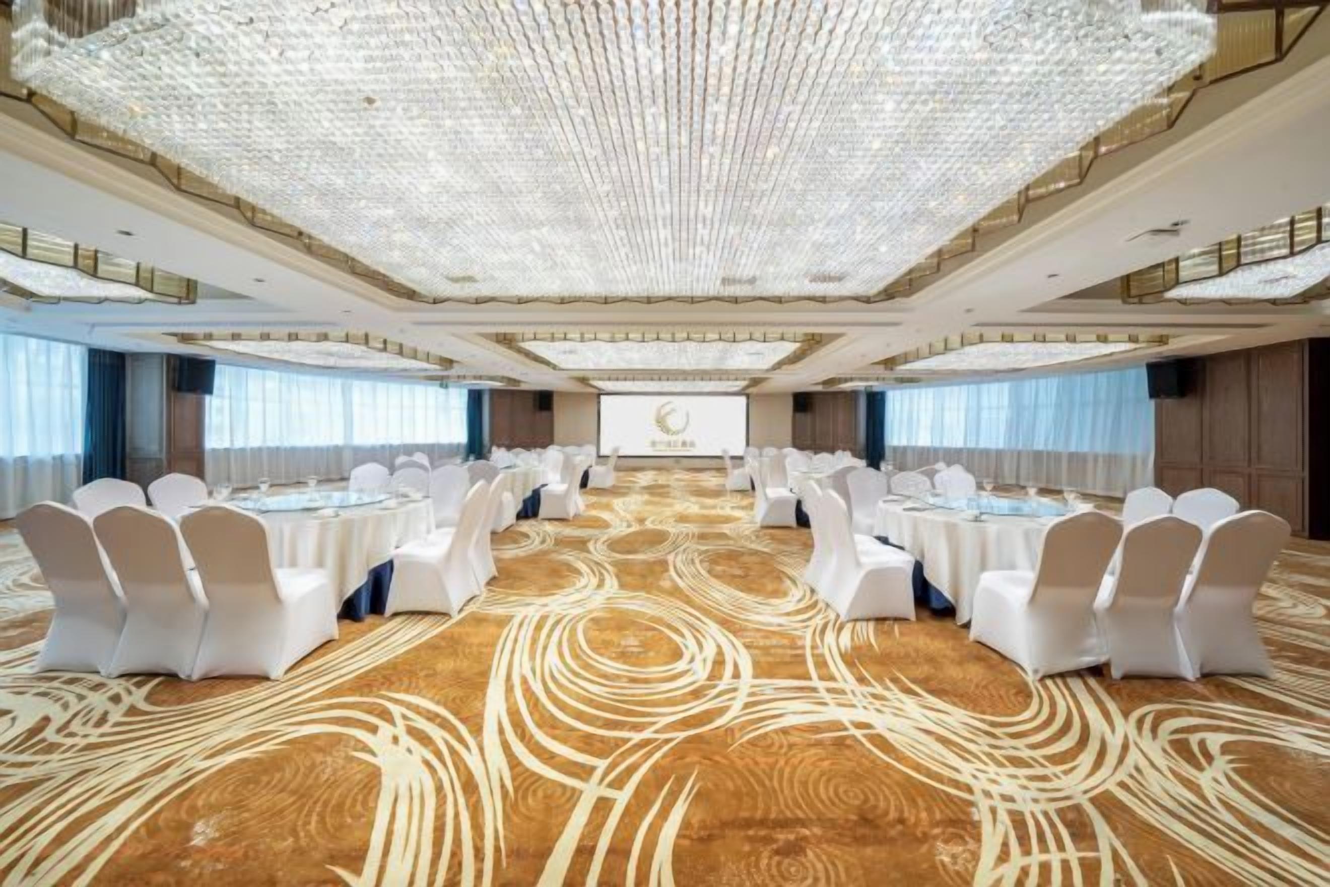A large conference room with a long table, white chairs, and a carpeted floor.