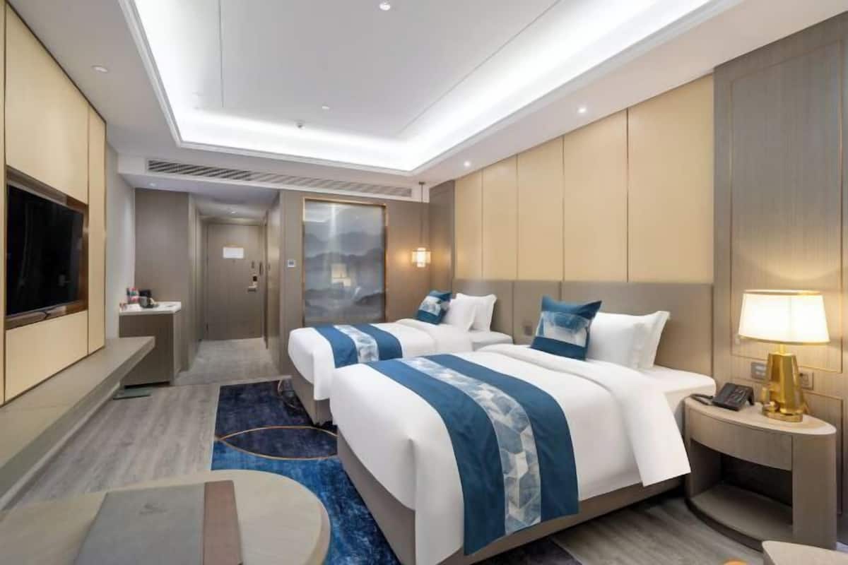 Une chambre d’hôtel avec deux lits, une télévision, un bureau et une salle de bain.