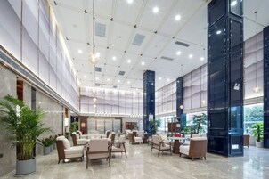 A spacious lobby with high ceilings, multiple seating areas, and large windows.