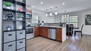 A modern kitchen with wooden cabinets, stainless steel appliances, and a built-in island. - Poconos Gem • Hot Tub • Near All Attractions (Tobyhanna)
