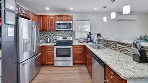 A modern kitchen with stainless steel appliances, wooden cabinets, granite countertops, and pendant lighting. - Poconos Gem • Hot Tub • Near All Attractions (Tobyhanna)