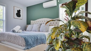 A bedroom with a bed, a large plant, and a wall-mounted air conditioner. - Poconos Gem • Hot Tub • Near All Attractions (Tobyhanna)