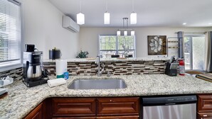 A modern kitchen with granite countertops, a built-in dishwasher, and a coffee maker. - Poconos Gem • Hot Tub • Near All Attractions (Tobyhanna)