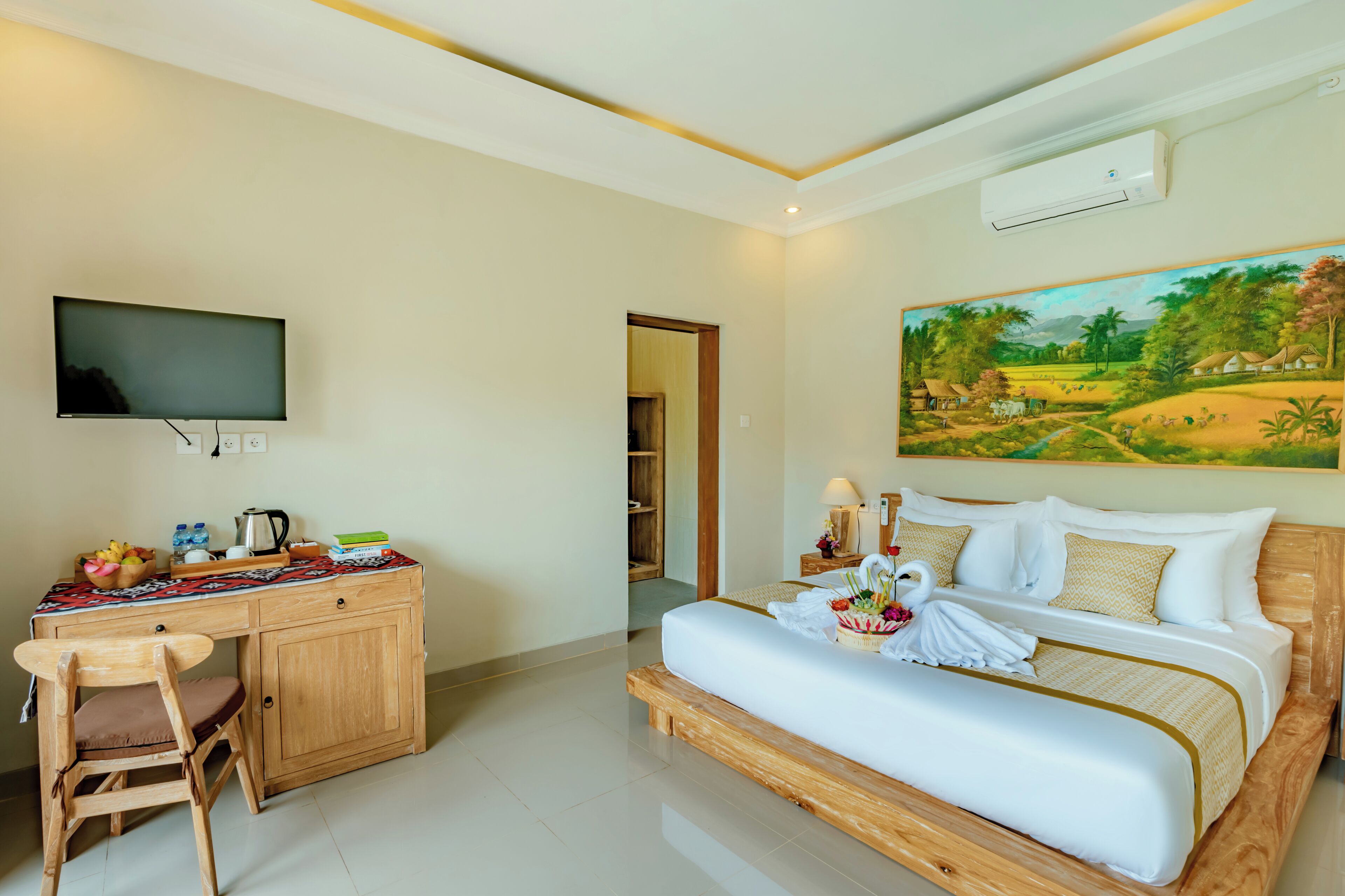 A hotel room with a bed, a desk with a chair, a television, and a painting on the wall.