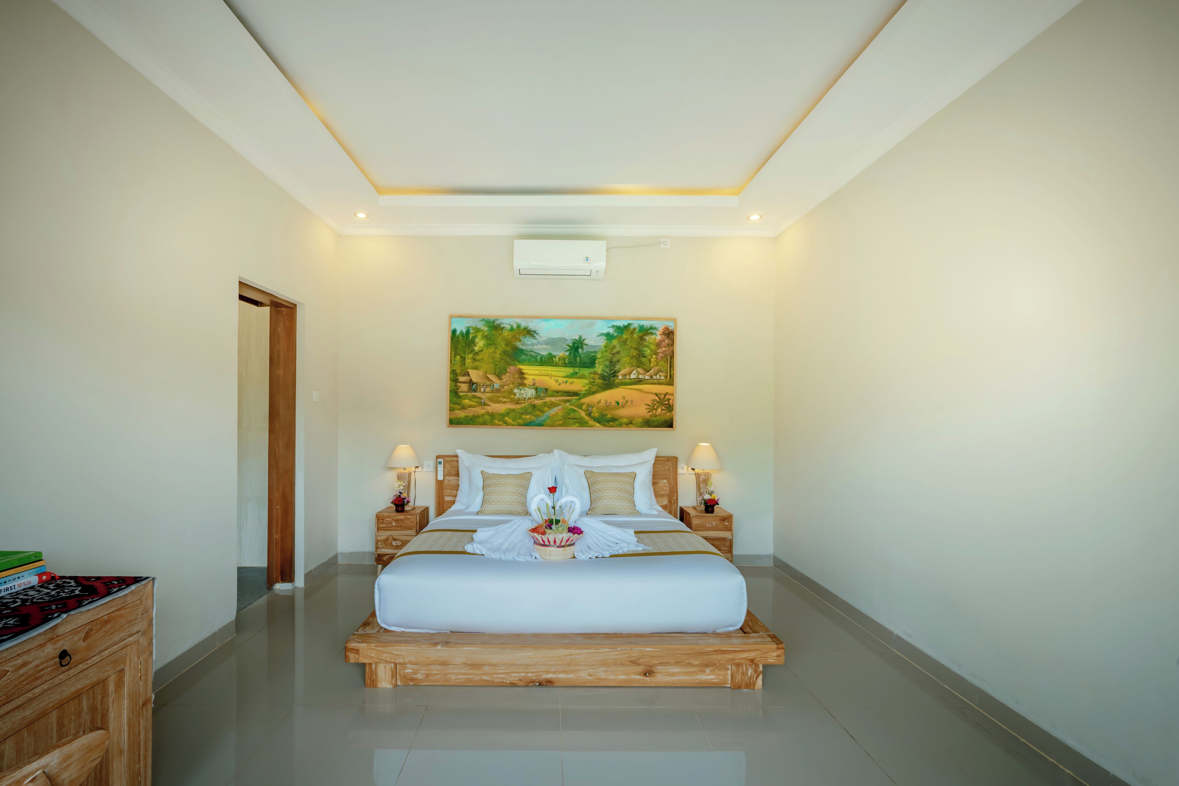 Une chambre spacieuse avec un grand lit, une tête de lit en bois et un tableau représentant un paysage.