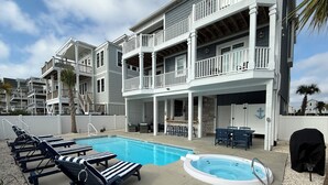 A pool area with lounge chairs, a hot tub, and a covered grill. - New Lagoon-Front Beach Home w/ Private Pool, Elevator, & Oceanfront Pool Access (Ocean Isle Beach)