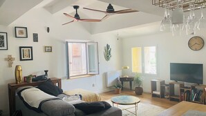 A living room with a grey sofa, a coffee table, a TV, and a ceiling fan. - Very atypical downtown apartment. Old oil mill! (La Crau)