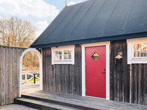 A wooden building with a red door, a small window, and a porch. - 4 Star Holiday Home in Drottningskar (Drottningskär)