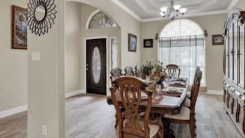 Comedor con mesa y sillas de madera, una araña y un aparador grande de madera con puertas de cristal.
