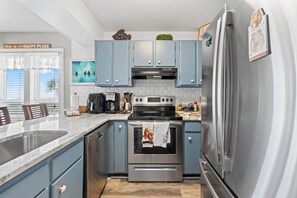 Una cocina moderna con alacenas azul claro, electrodomésticos de acero inoxidable y encimera de mármol.