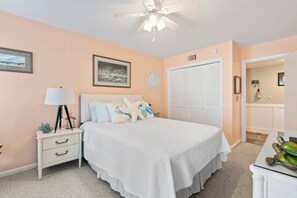 Une chambre à coucher avec un lit, une table de chevet, une lampe et un ventilateur de plafond.