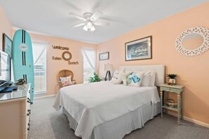 Un dormitorio con cama, ventilador de techo, tabla de surf y una pared con un cartel que dice 'Welcome Relax Beach'.