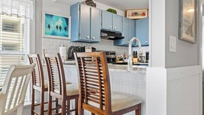 Une cuisine dotée d’un îlot central, de tabourets de bar et d’une table à manger avec des chaises.
