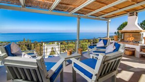 A covered outdoor seating area with a view of the sea, featuring wooden furniture and a barbecue. - Villa Thea by Villa Plus (Ionian Islands)