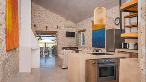 A modern kitchen with a central island, built-in oven, and a stone wall backdrop.