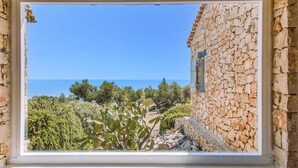 A stone building with a window overlooking a coastal landscape.