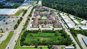 Luchtbeeld van een woongebied met meerdere tweelaagse huizen, een centraal gelegen zwembad en een ruime parkeerplaats.
