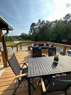 Eine Holzterrasse mit Tisch und Stühlen mit Blick auf einen See und Wald.