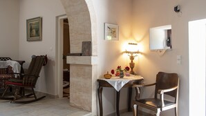 Une pièce avec un fauteuil à bascule, une table avec une lampe et un miroir au mur.