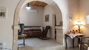 Une pièce avec une arche en pierre, un canapé, un fauteuil à bascule, une table avec une lampe et un téléviseur.